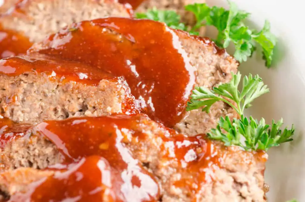 A close up picture of Meatloaf slices with delicious red sauce drizzled over the top - The Goldilocks Kitchen