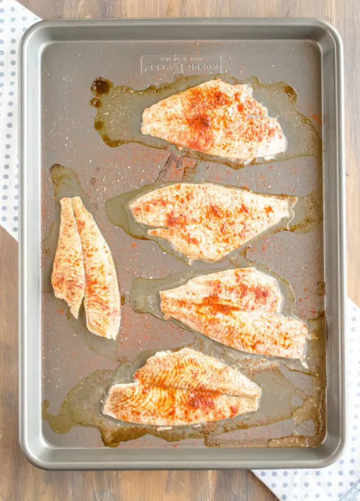 A sheet pan with white fish filets sprinkled with seasonings for Baja Fish Tacos - The Goldilocks Kitchen