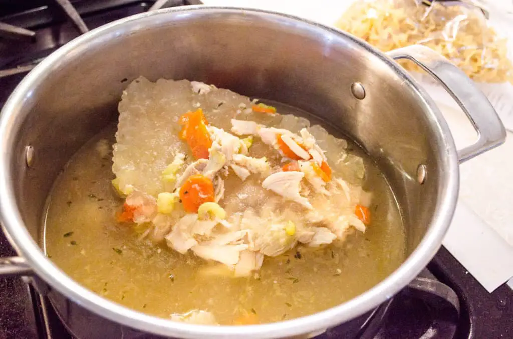 Frozen Make Ahead Chicken Noodle Soup thawing out in a pot - The Goldilocks Kitchen