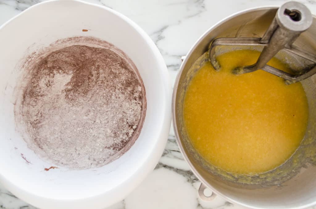 Two bowls, one white, one stainless steel, hold dry and wet ingredients to make Applesauce Picnic Cake - The Goldilocks Kitchen