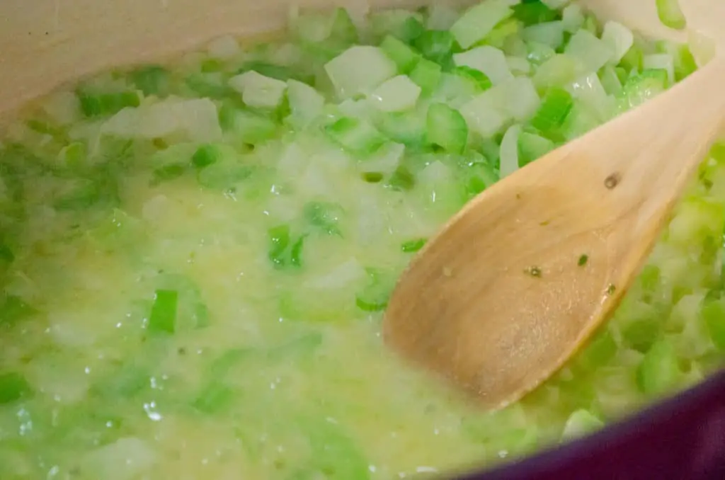 Onion and celery cook in butter in the bottom of a dutch oven to make Chicken and Wild Rice Soup - The Goldilocks Kitchen