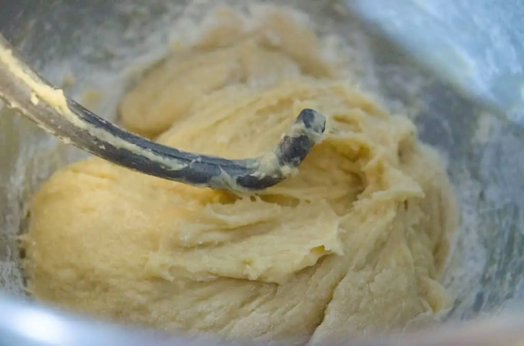  Braided Challah Bread dough sits in the bottom of a stand mixer bowl with a dough hook on top- The Goldilocks Kitchen