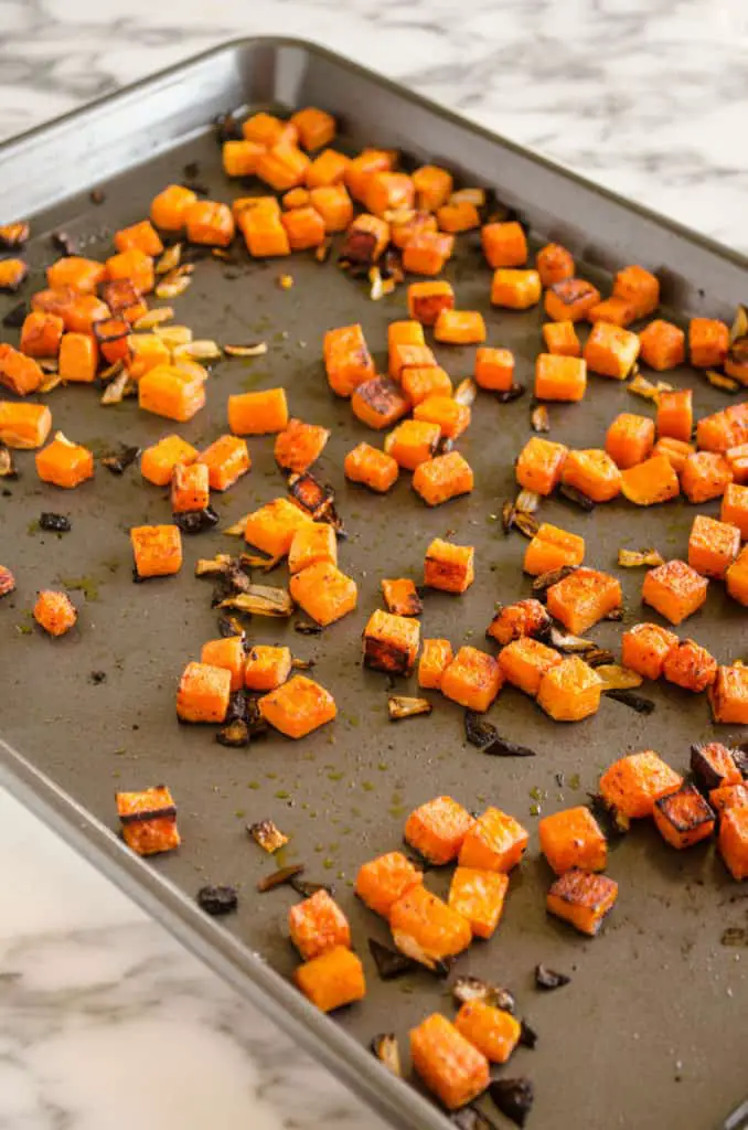 Cubed roasted butternut squash in a rimmed baking sheet used to make Grilled Chicken Tacos with Green Chile Cream Sauce - The Goldilocks Kitchen