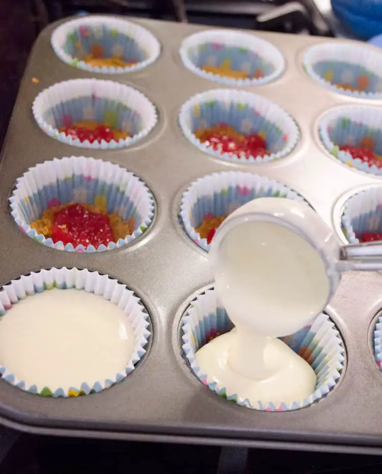 Cheesecake batter is placed in cupcake liners in a muffin tin to make Strawberry Mini-Cheesecakes - The Goldilocks Kitchen
