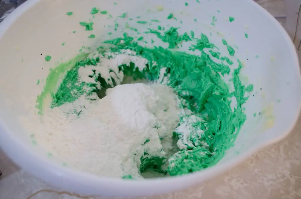Flour and salt is added to green dough to make St. Patricks Day Cream Cheese Spritz Cookies - The Goldilocks Kitchen