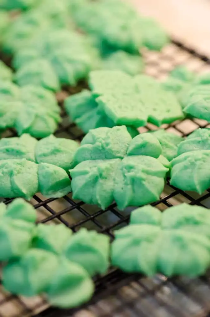 A close up picture of St. Patricks Day Cream Cheese Spritz Cookies cooling on a wire rack - The Goldilocks Kitchen