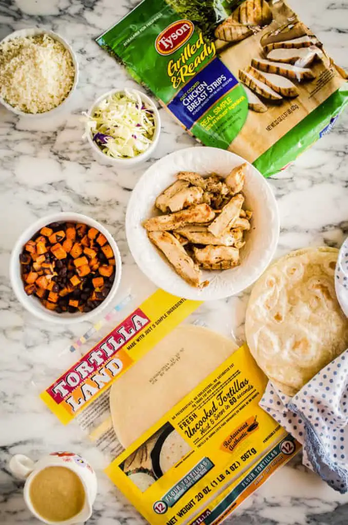 All ingredients to make Grilled Chicken Tacos with Green Chile Cream Sauce spread out on a marble counter - The Goldilocks Kitchen