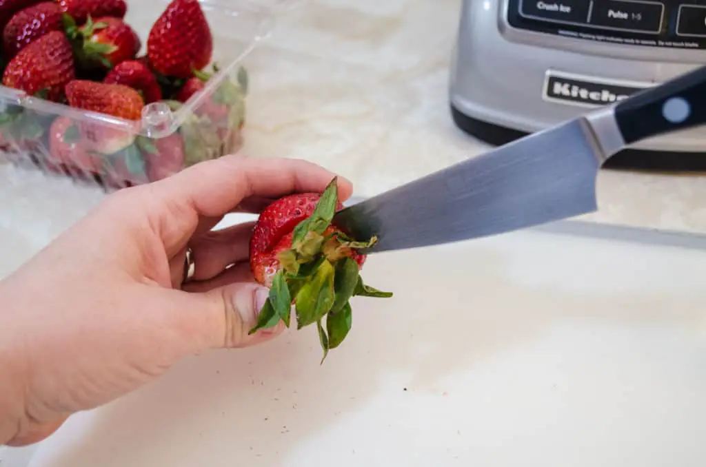 Hulling a strawberry for Fresh Sparkling Strawberry Lemonade - The Goldilocks Kitchen