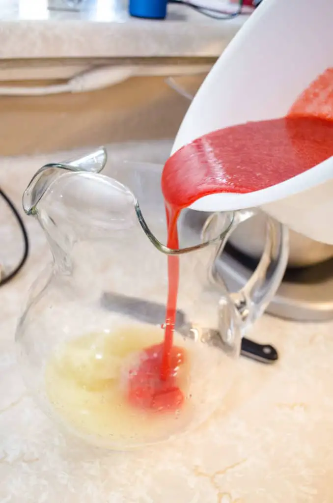 Strawberry puree is poured into a glass pitcher with freshly squeezed lemon juice to make Fresh Sparkling Strawberry Lemonade - The Goldilocks Kitchen