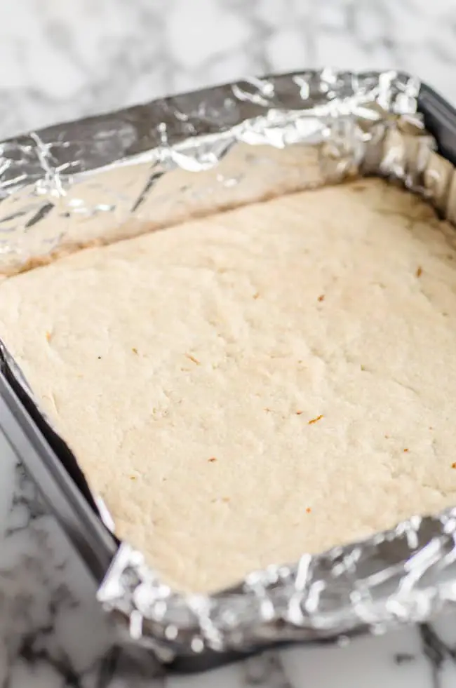 A 9 x 9 pan with baked almond shortbread crust for Goldilocks Kitchen Lemon Bars - The Goldilocks Kitchen