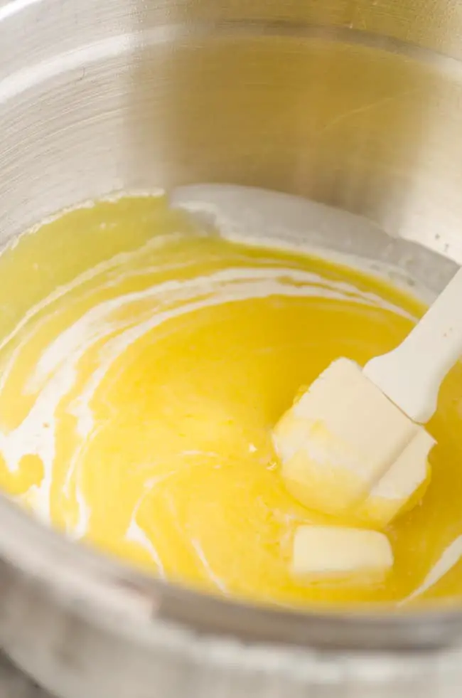 White streaks of heavy cream stirred into a lemon curd mixture in a mixing bowl to make Goldilocks Kitchen Lemon Bars - The Goldilocks Kitchen