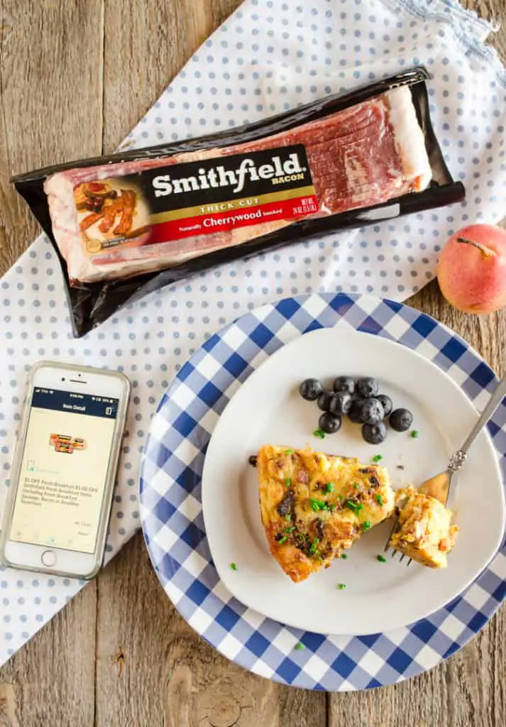 Looking down on a plate with a slice of Bacon Cheddar 30 Minute Skillet Strata next to an iPhone with a coupon displayed next to a package of Smithfield Bacon for Bacon Cheddar 30 Minute Skillet Strata - The Goldilocks Kitchen - The Goldilocks Kitchen 