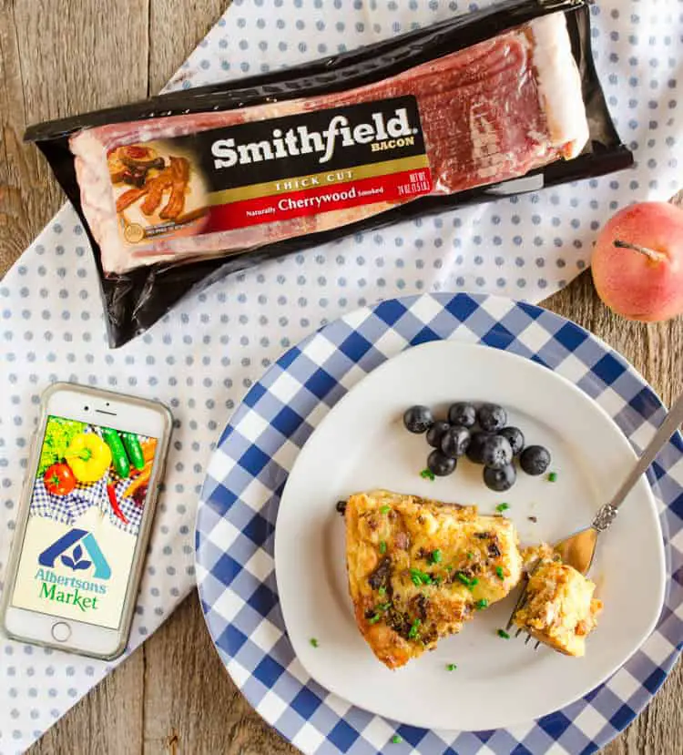 Bacon Cheddar 30 Minute Skillet Strata slice on a plate next to a package of Smithfield Bacon and an iPhone with the Albertsons Market logo - The Goldilocks Kitchen