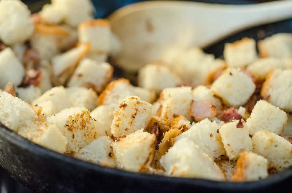 Cubes of hearty bread toast in a cast-iron skillet to make a Bacon Cheddar 30 Minute Skillet Strata - The Goldilocks Kitchen 