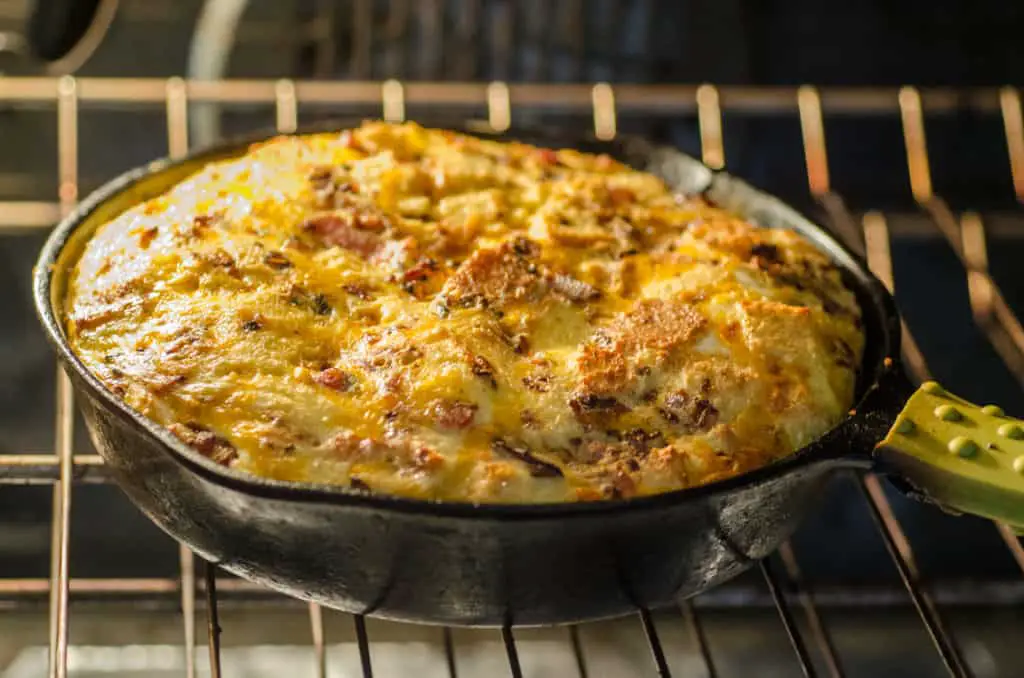 A puffed up Bacon Cheddar 30 Minute Skillet Strata bakes in a cast-iron skillet - The Goldilocks Kitchen 