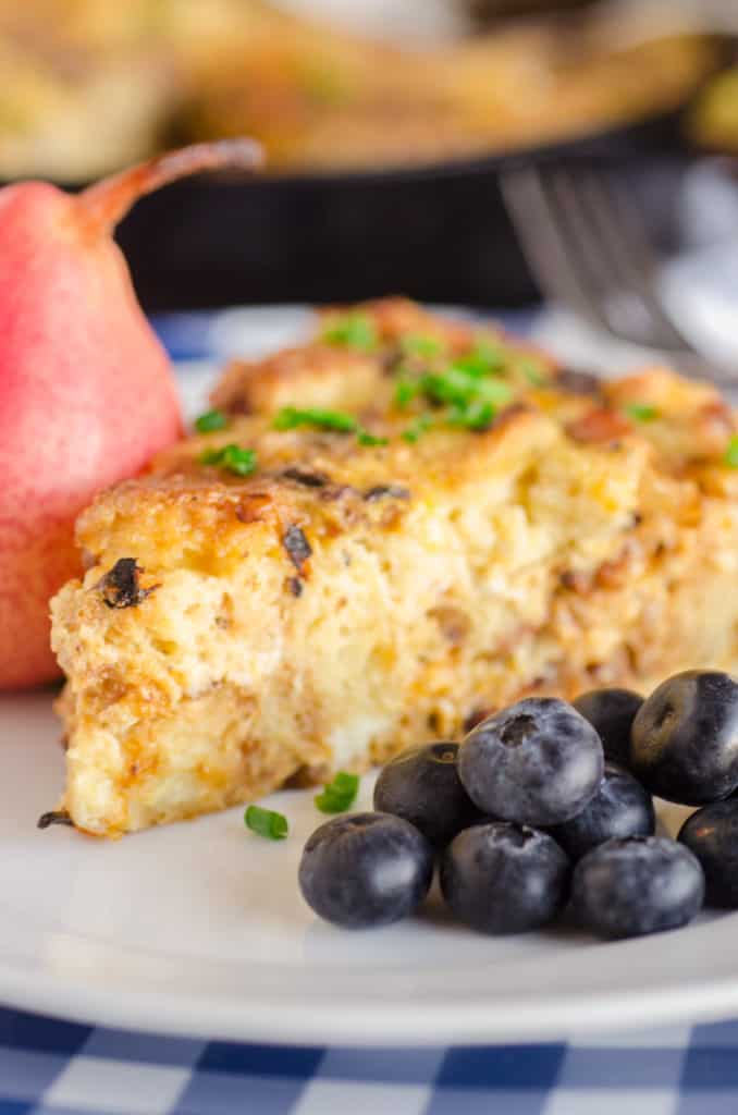 Bacon Cheddar 30 Minute Skillet Strata slice with some blueberries on the side - The Goldilocks Kitchen