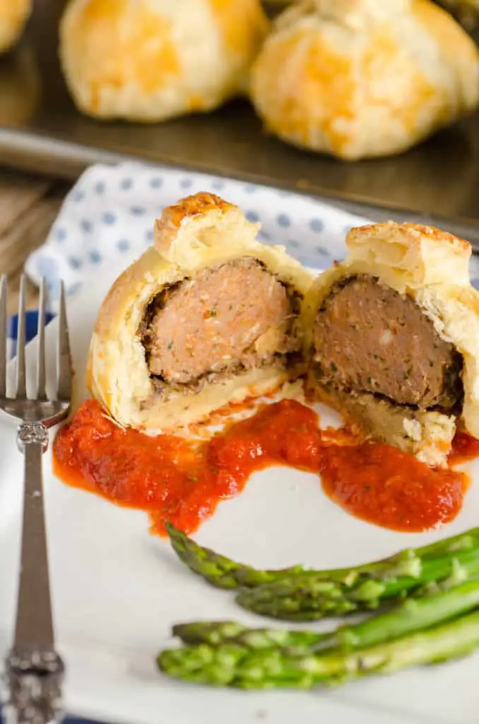 Easy Meatball Wellingtons made with Carando brand meatballs. One is sliced open on a plate showing the meatball center. - The Goldilocks Kitchen