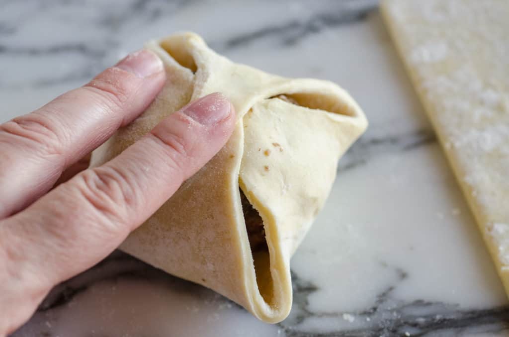 A meatball is covered with puff pastry dough to make Easy Meatball Wellingtons - The Goldilocks Kitchen