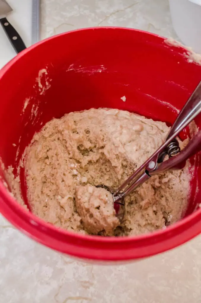 A red mixing bowl containing Apple Cinnamon Cupcakes batter with a scoop- The Goldilocks Kitchen