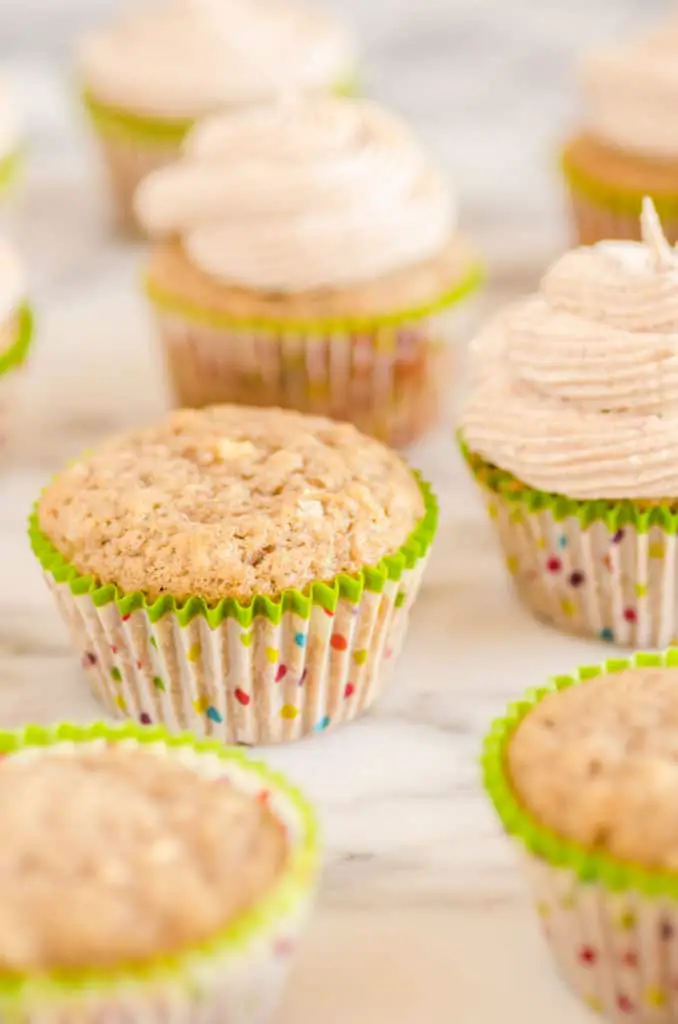 Apple Cinnamon Cupcakes sit on a marble counter, some frosted some plain. - The Goldilocks Kitchen