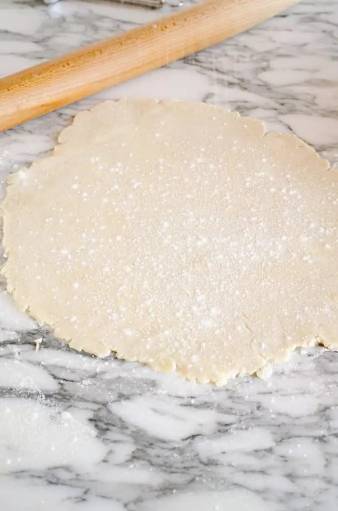 Pie crust dough is rolled out and lightly floured on a marble counter to show How to prebake pie crust - The Goldilocks Kitchen