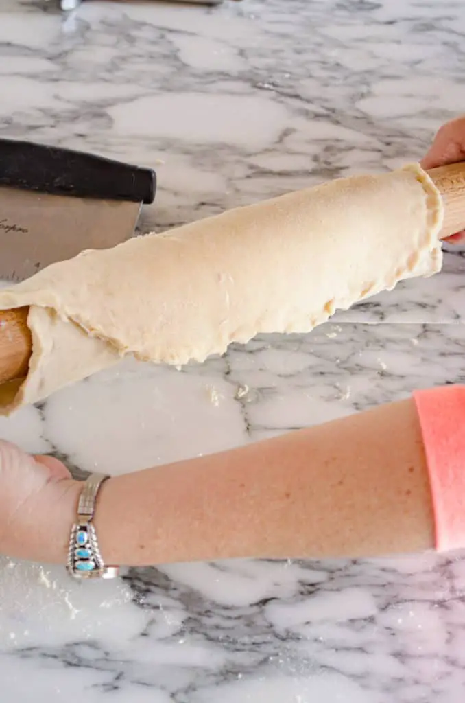 Dough for a pie crust is rolled around a french rolling pin to show how to prebake a pie crust - The Goldilocks Kitchen