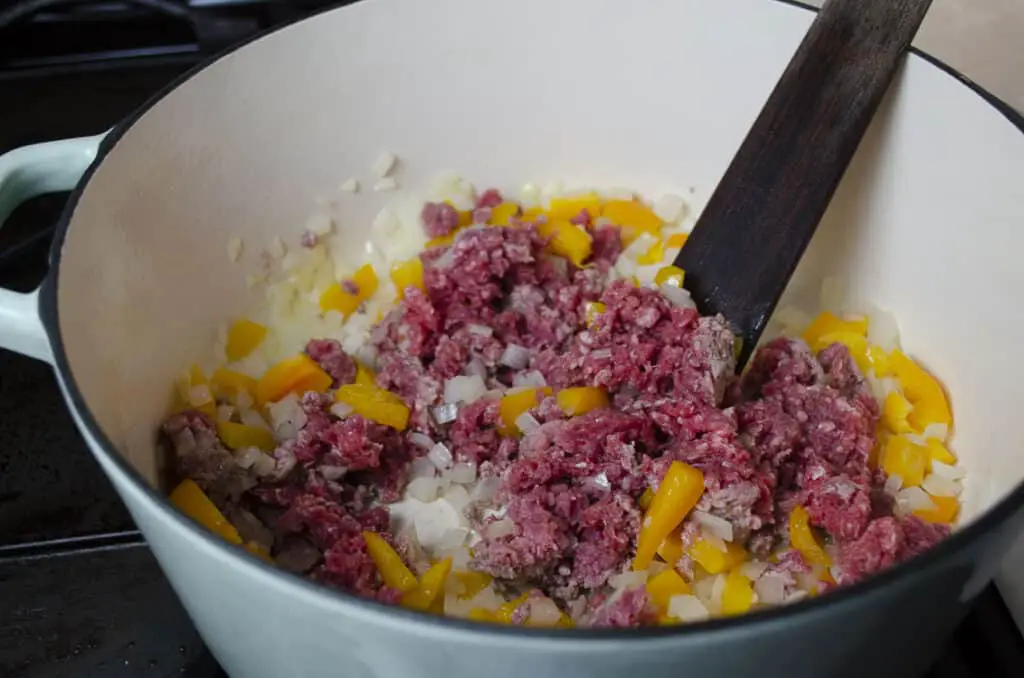 Chopped onion, yellow bell pepper and ground beef cook together in a stovetop Dutch oven.