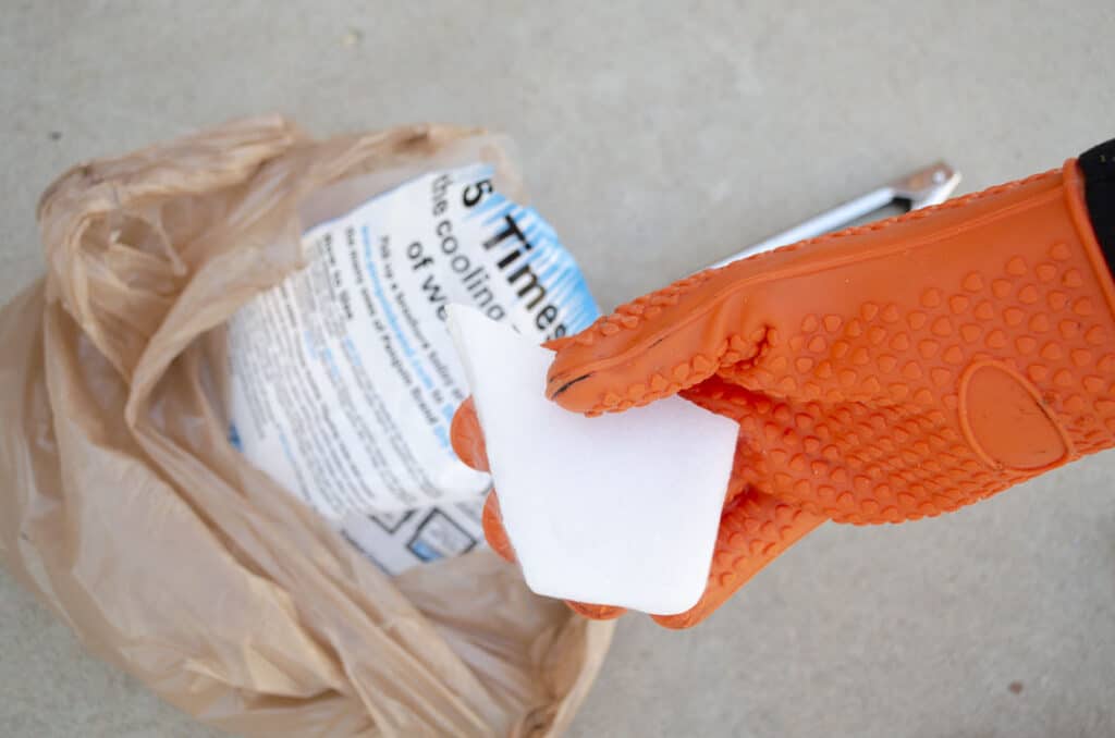 A gloved hand holds a white chunk of dry ice.