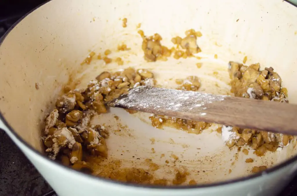 Flour is stirred into sauteed mushrooms and onions.