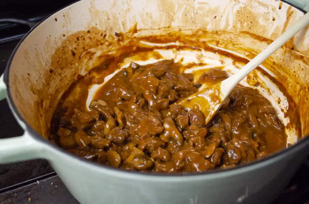 Baking Savory Beef Pot Pie filling in a Dutch oven has created a silky dark brown sauce surrounding the pie filling.