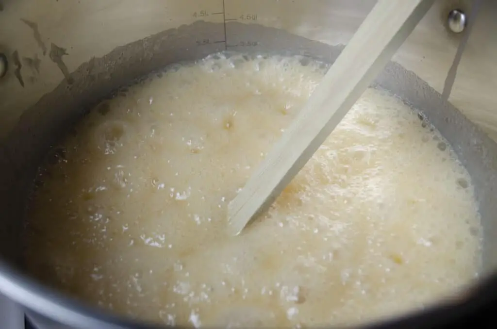 A mixture of butter, evaporated milk and sugar is at a rolling boil in a stock pot to make Blue-Ribbon Fudge.