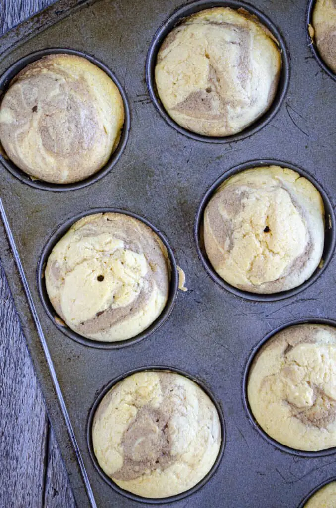 Looking down on a muffin tin filled with   freshly baked Snickerdoodle Pumpkin Muffins.