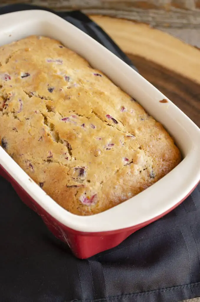 A freshly baked loaf of Frosted Cranberry Nut Bread still in the loaf pan.