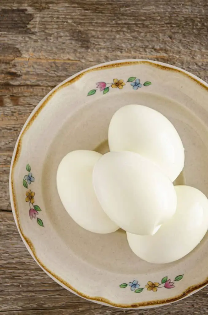 A pyramid of Easy-Peel Boiled eggs on a decorative plate sits on a wooden table. 