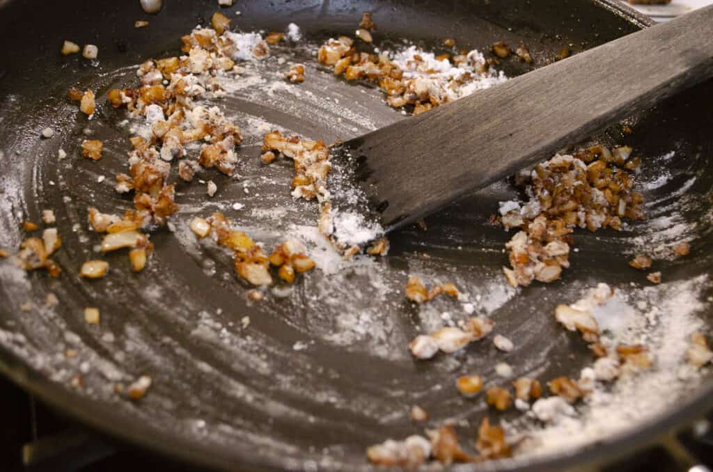 Chopped onion and flour is cooked in beef meatball drippings in a large skillet.