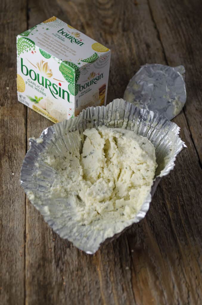 A box of Boursin Cheese with it's contents sitting opened next to it.