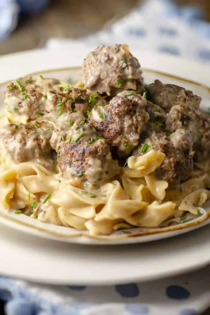 A close-up picture of a 30-minute One-Pot Meatball Stroganoff serving on a plate showing the texture and minced chives sprinkled on top.