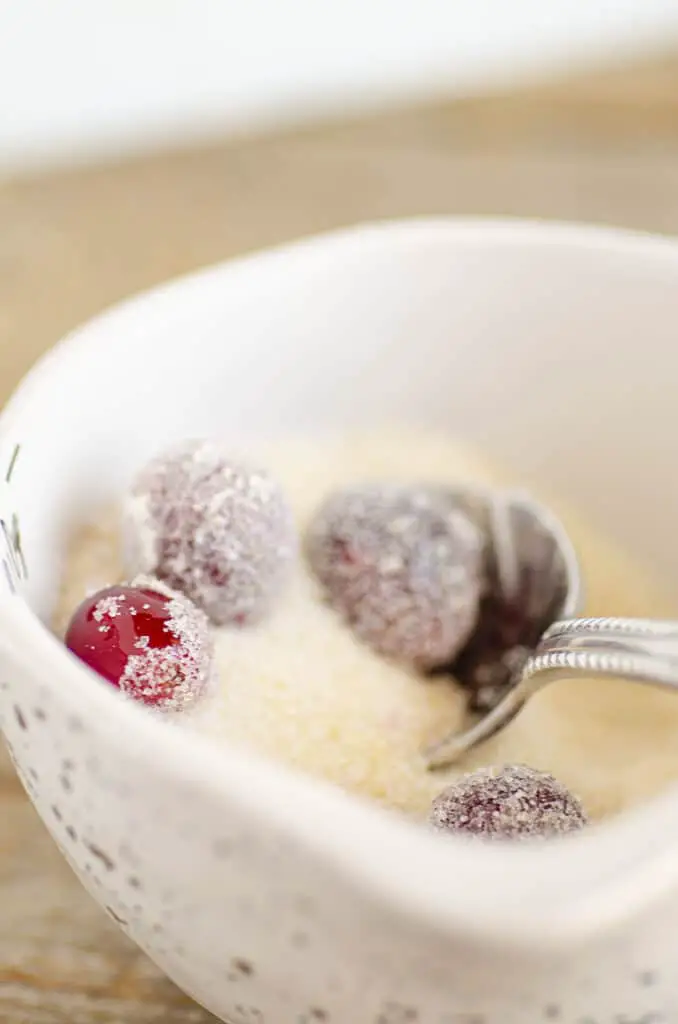 Syrup-covered red cranberries get their sugar coating in a bowl of mixed sugars.