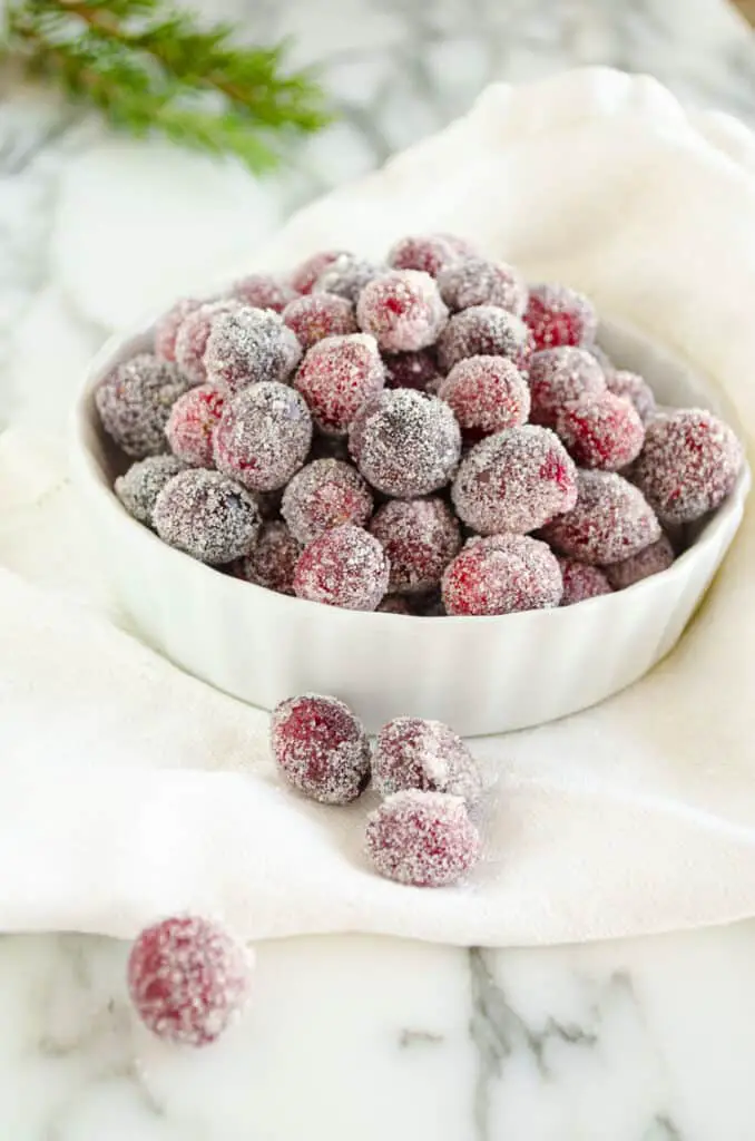 A close-up of Sparkling Sugared Cranberries in a white bowl.
