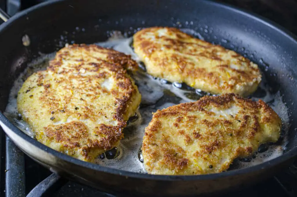 Sweet Lemon Chicken Piccata cutlets frying in caper-infused butter.