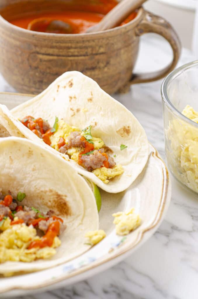 A look at a Soft Fiesta Breakfast Taco with Sausage & Red Chile Sauce stuffed inside garnished with freshly minced green cilantro and fresh lime juice.