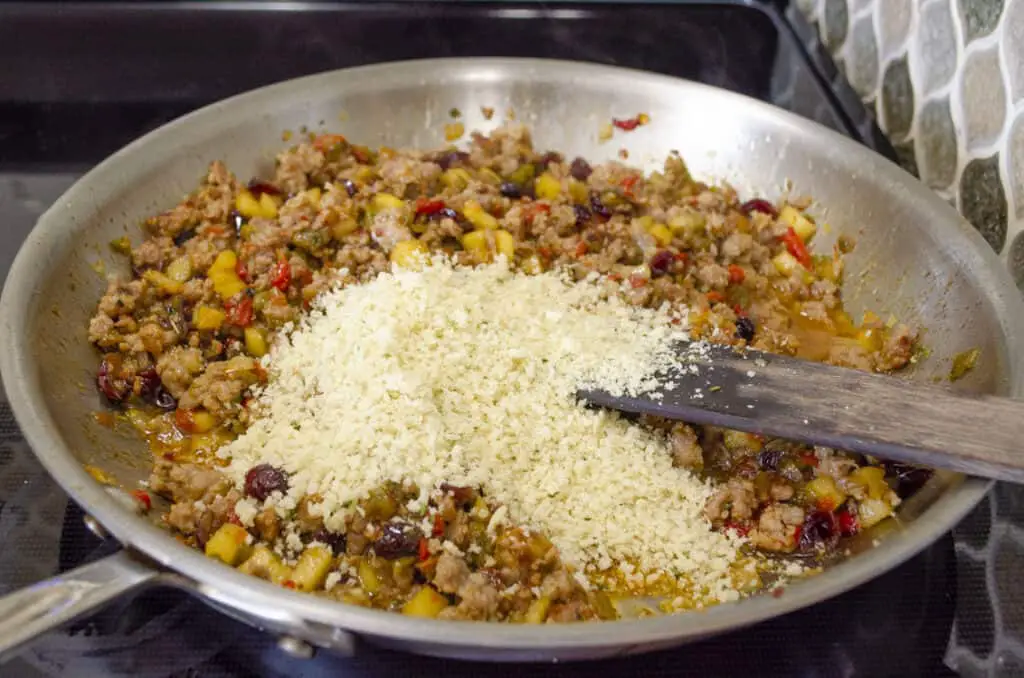 Panko bread crumbs are added to the ingredients in the aluminum pan to finalize the stuffing for Green chile and Sausage stuffed Acorn Squash.