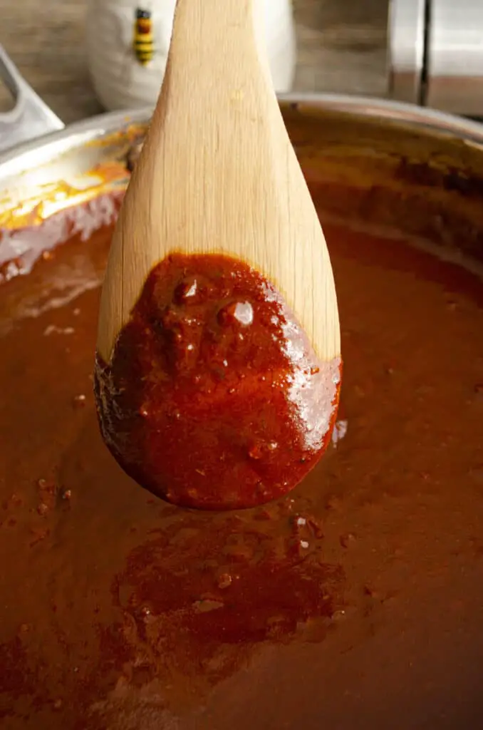  Red chile sauce napes to the back of a wooden spoon.