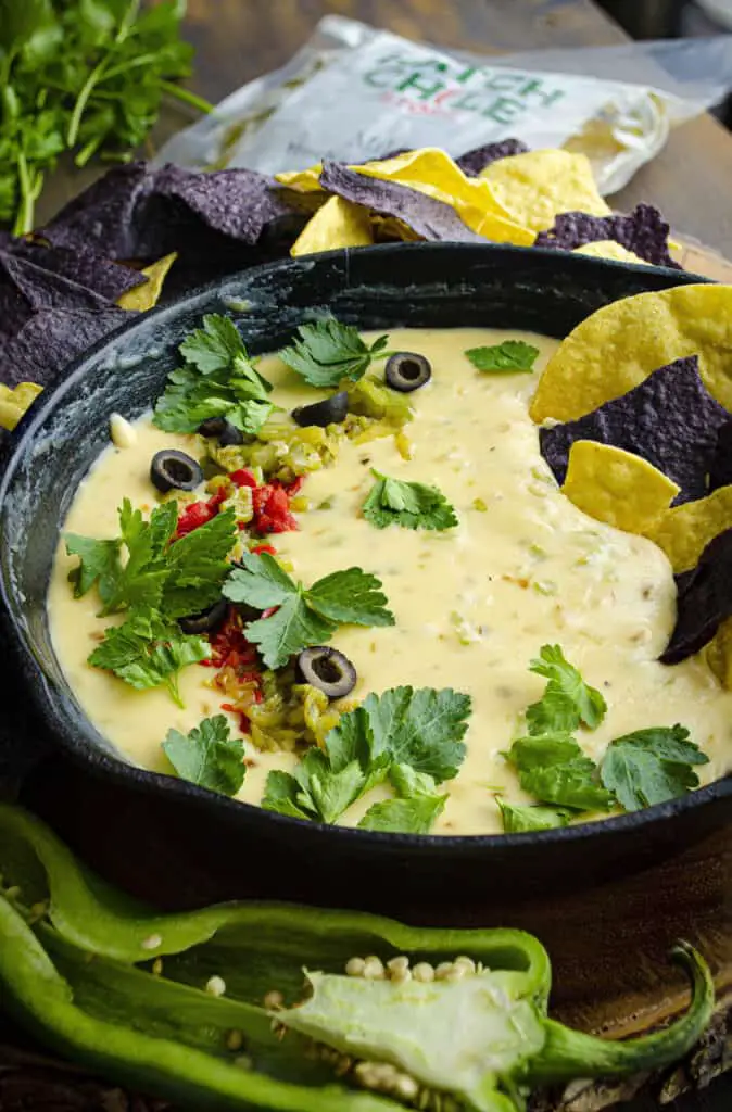 A closeup picture of a cast iron skillet with melty Hatch Green Chile queso in it.