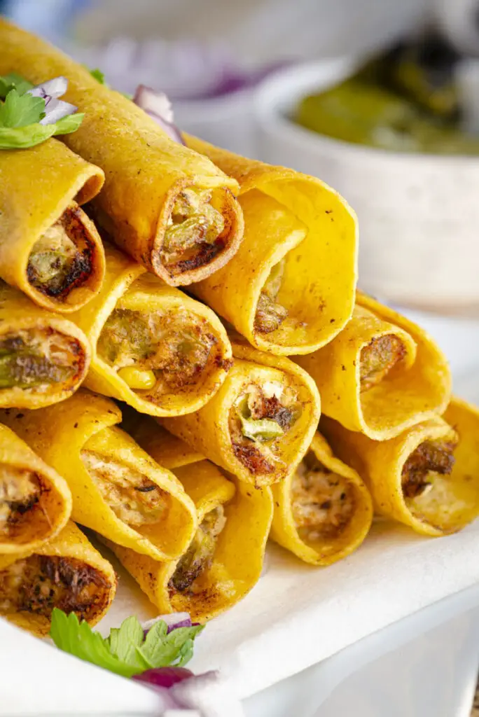 A very closeup picture looking inside of several stacked Green Chile Chicken taquitos showing the stuffing inside.