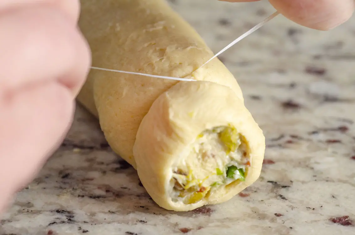 A gallery of three images demonstrating how to slice a roll of stuffed dough with floss.