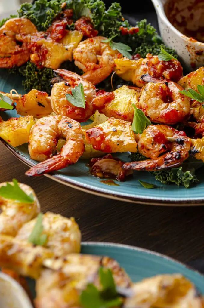 A closeup of three skewers of shrimp glazed with Sweet and Spicy Hatch chile glaze (red chile).