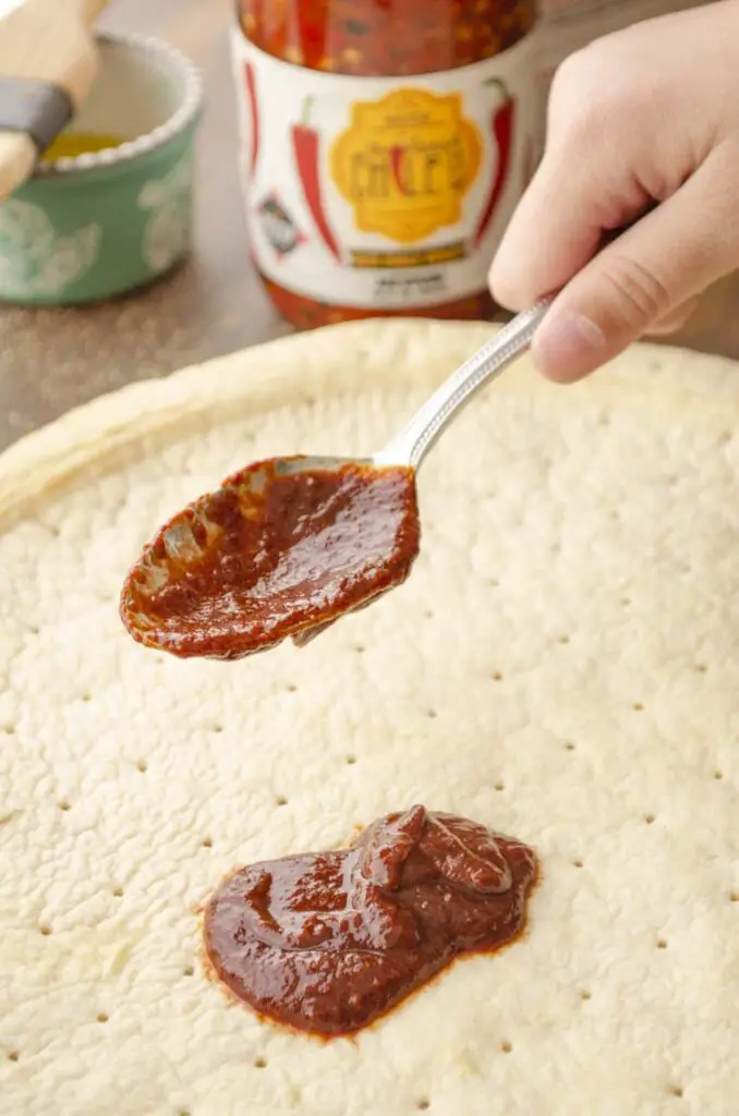 A spoonful of Hatch Red chile sauce is used instead of marinara sauce as the base of this pizza.
