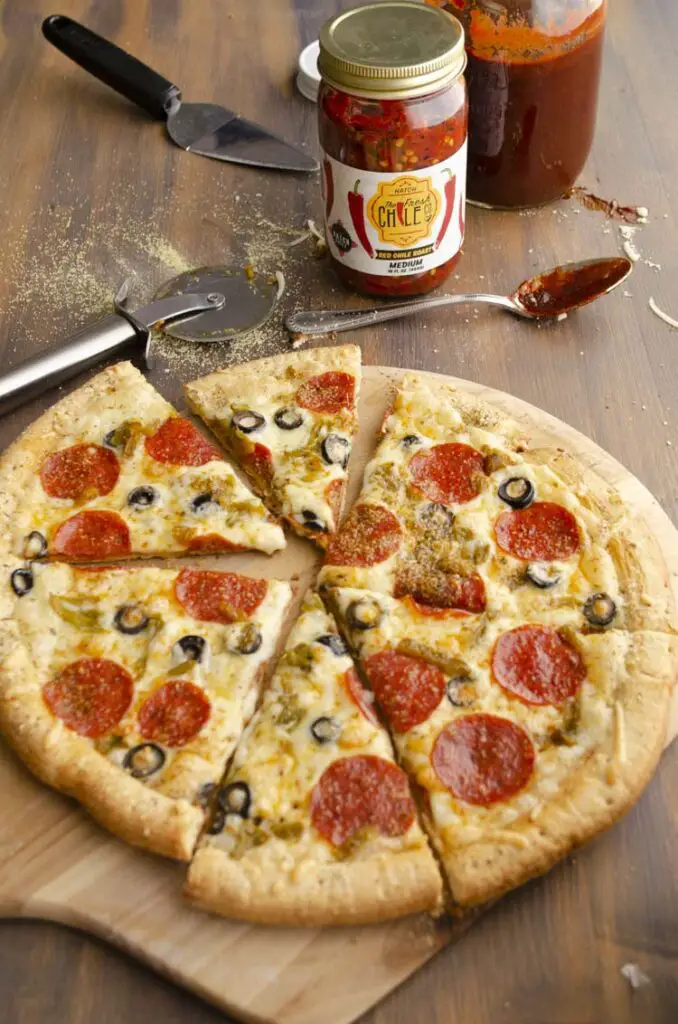 A freshly baked Spicy Lover's Copycat Pizza sits on a pizza peel and is sliced and ready to serve. 