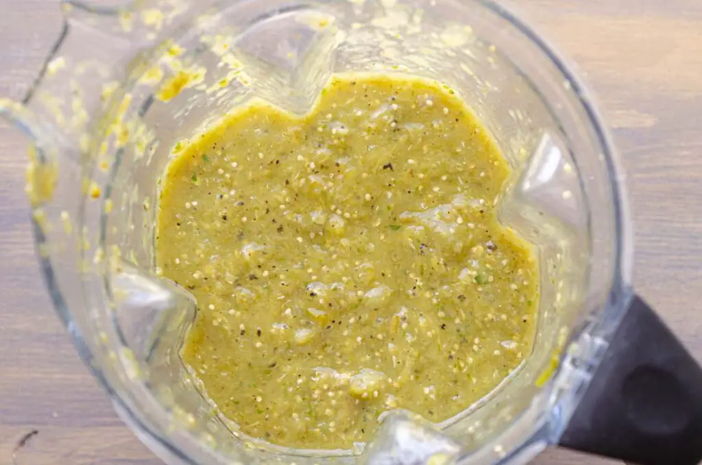 looking down into a blender full of blended green chili salsa.